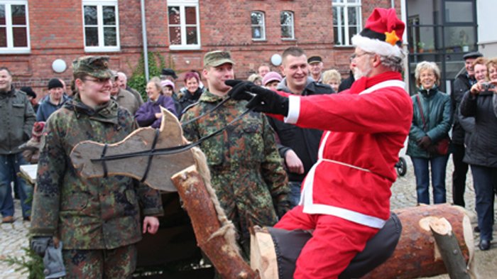 öffnet internen Link in aktuellem Fenster zeigt den Weihnachtsmann auf einem Holzpferd und umstehende Personen