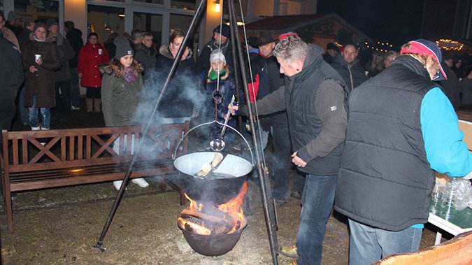 öffnet internen Link in aktuellem Fenster zeigt Personen, die Feuerzangenbowle zubereiten und Festbesucher