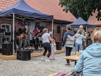 zeigt Band beim Bühnenauftritt und tanzende und zuhörende Besucher