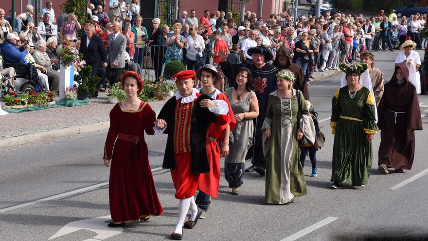 öffnet internen Link in aktuellem Fenster zeigt Abschnitt des Festumzugs mit historisch gekleideten Menschen und Zuschauergruppen am Straßenrand