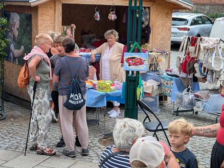 zeigt Marktstand und Personen davor