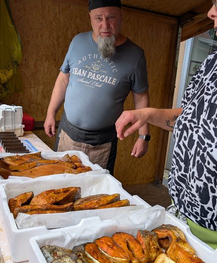 zeigt Marktstand mit geräuchertem Fisch und Personal
