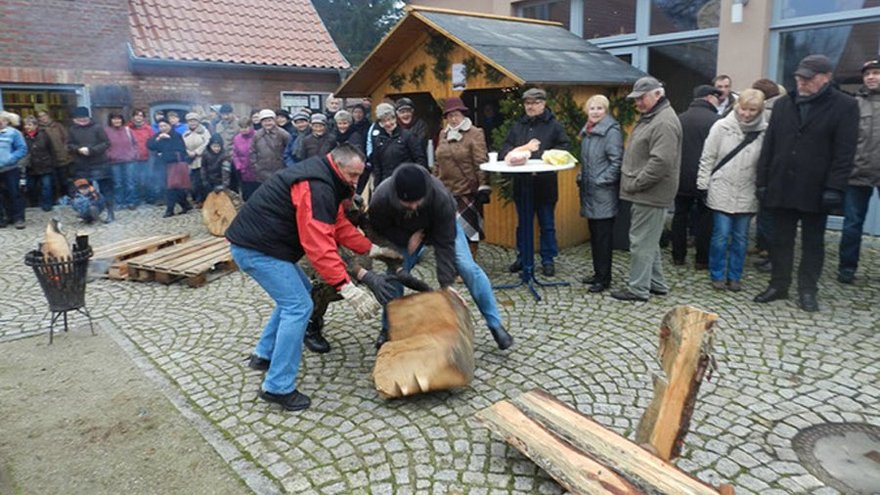 öffnet internen Link in aktuellem Fenster zeigt Männer beim Wettstreit mit Holzstücken und Zuschauergruppen