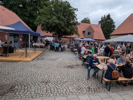 zeigt Blick auf die Festbesucher auf dem Platz und eine Bühne
