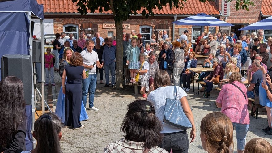 öffnet internen Link in aktuellem Fenster zeigt Blick auf den Festplatz mit einer großen Menschengruppe, die Personen vor einer Bühne zuhören und zuschauen