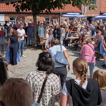 zeigt Menschengruppe vor einer Bühne